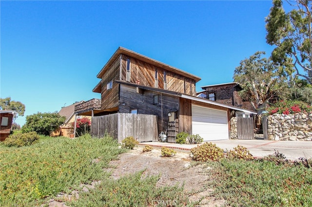 contemporary home featuring fence, concrete driveway, and an attached garage