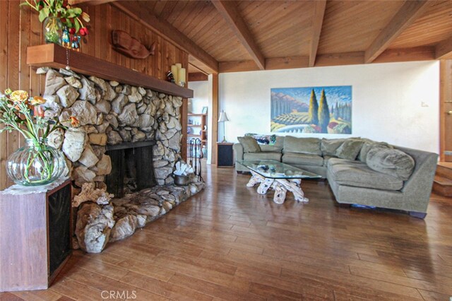 living room with wood walls, beam ceiling, dark wood-type flooring, wooden ceiling, and a fireplace