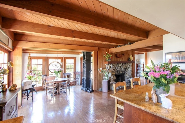 dining area with beamed ceiling, a fireplace, light wood-type flooring, and wooden ceiling