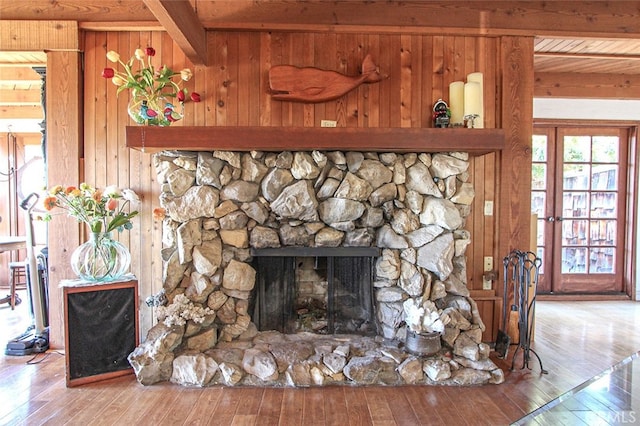 details featuring wood walls, wooden ceiling, beam ceiling, a fireplace, and wood finished floors