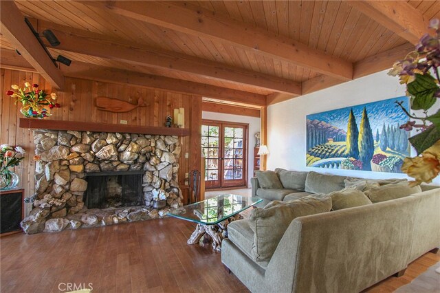 living room featuring wood ceiling, hardwood / wood-style flooring, beam ceiling, wooden walls, and a stone fireplace