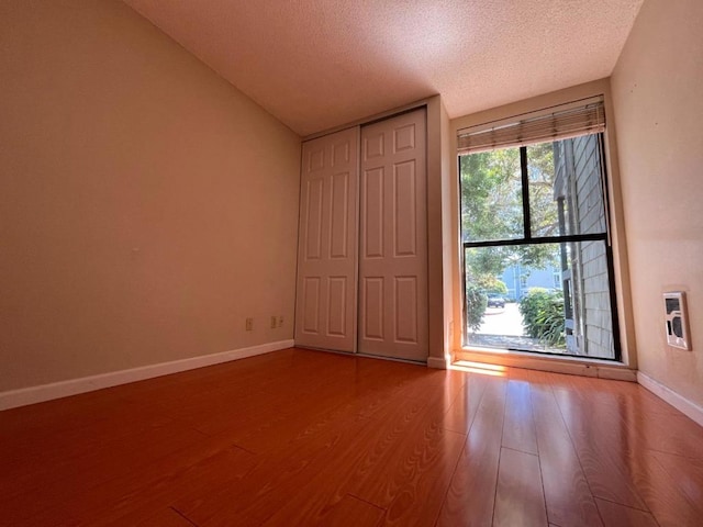 unfurnished bedroom with heating unit, hardwood / wood-style floors, a closet, and a textured ceiling