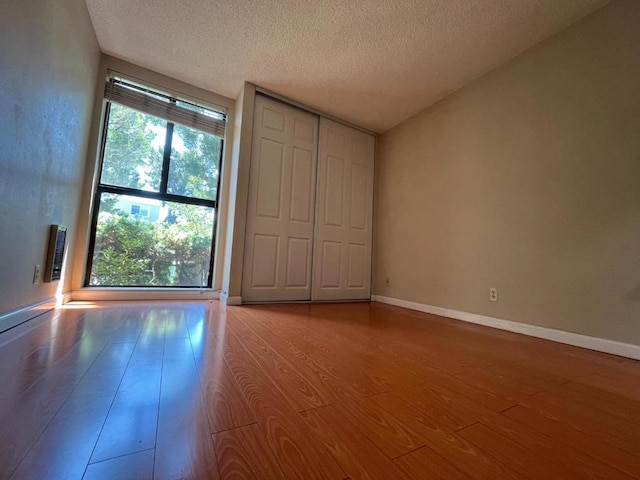 unfurnished bedroom featuring a closet, a textured ceiling, and light wood-type flooring