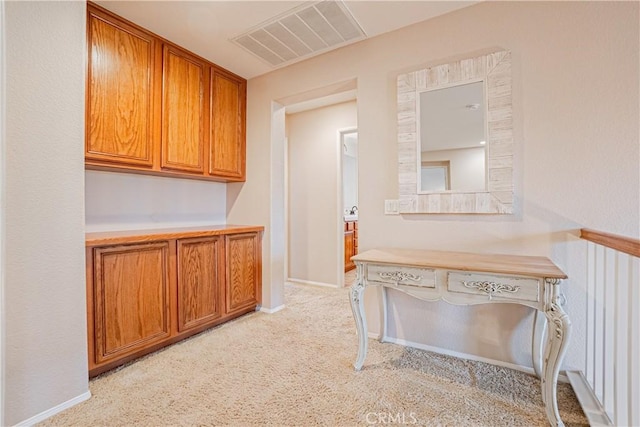 hall featuring light colored carpet, visible vents, and baseboards