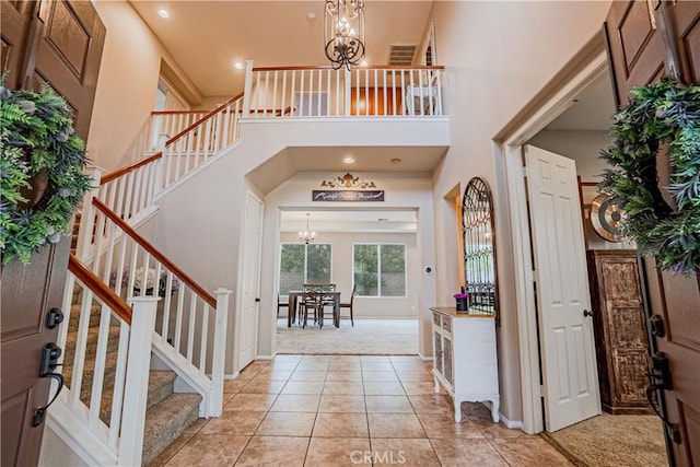 foyer with a notable chandelier, light tile patterned flooring, and a towering ceiling