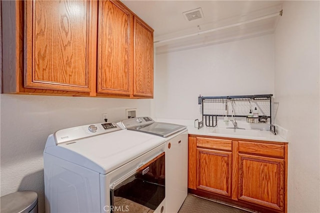 laundry room with a sink, visible vents, washing machine and clothes dryer, and cabinet space