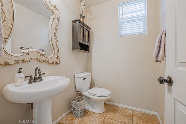 half bathroom with tile patterned flooring, toilet, and baseboards