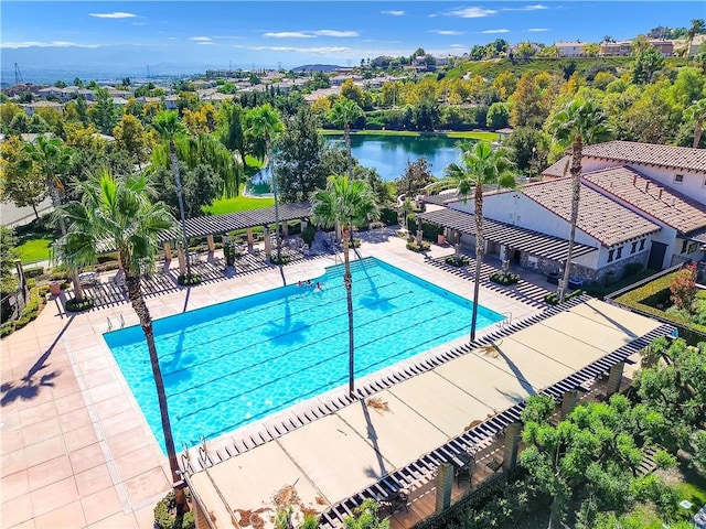 community pool featuring a water view, fence, and a patio