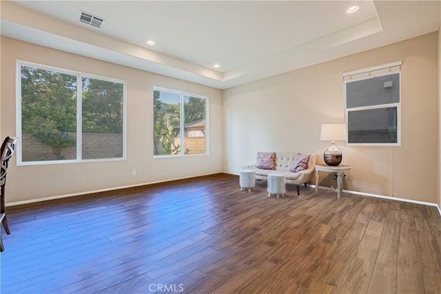 living area with recessed lighting, a raised ceiling, visible vents, wood finished floors, and baseboards