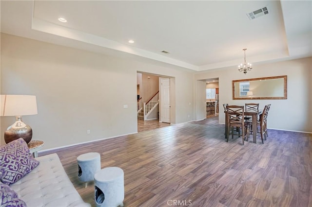 dining room with a raised ceiling, visible vents, stairway, and wood finished floors