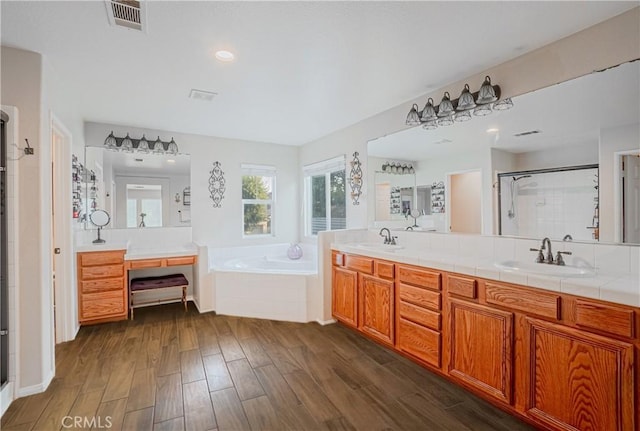 bathroom with a garden tub, visible vents, a stall shower, a sink, and wood finished floors