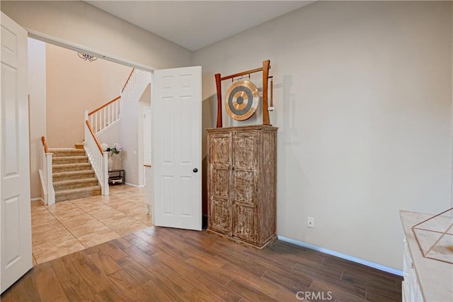 foyer entrance featuring stairway, baseboards, and wood finished floors