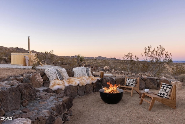 yard at dusk featuring a mountain view and a fire pit