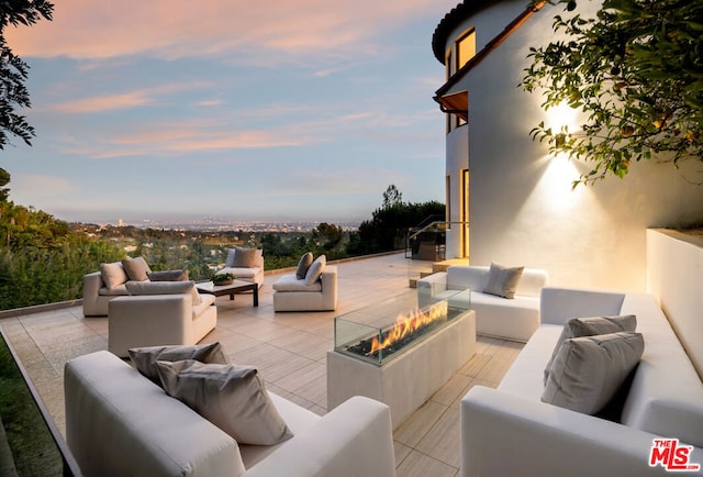 patio terrace at dusk featuring an outdoor living space with a fire pit