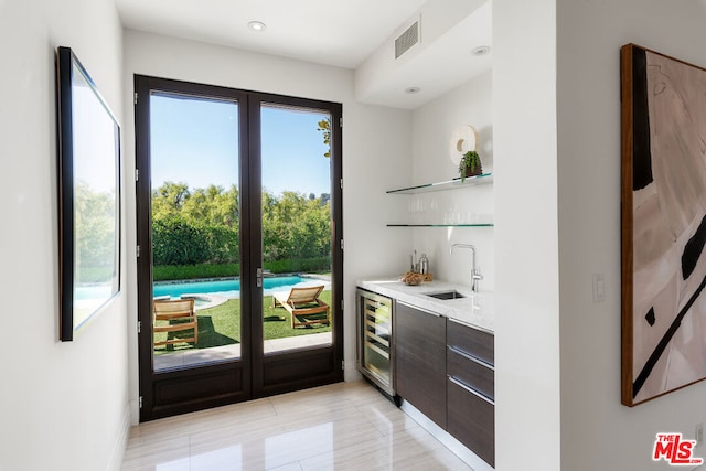 doorway featuring wine cooler, indoor wet bar, and light tile patterned flooring