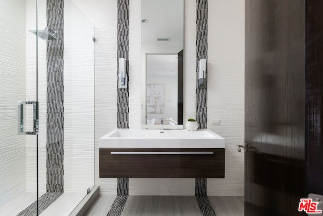 bathroom with vanity, a shower with shower door, and tile walls