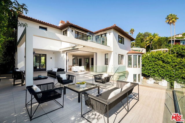 back of property featuring a balcony, an outdoor hangout area, and a patio