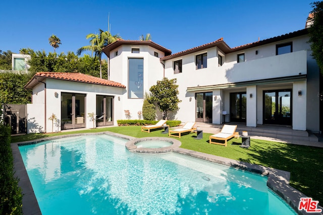 back of house with a lawn, a patio area, french doors, and a pool with hot tub