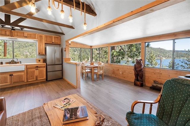 kitchen featuring vaulted ceiling with beams, stainless steel refrigerator, a water view, and plenty of natural light