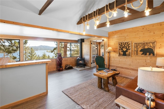 living room featuring wood-type flooring, a mountain view, a wood stove, wooden walls, and vaulted ceiling with beams