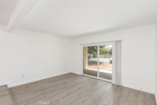 unfurnished room with beam ceiling, a textured ceiling, and hardwood / wood-style floors