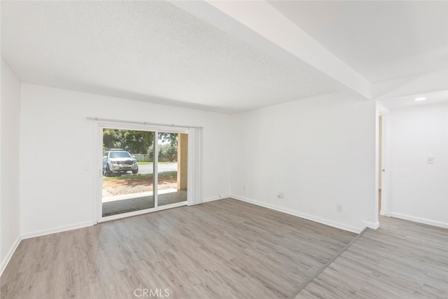 spare room featuring a textured ceiling and light hardwood / wood-style floors