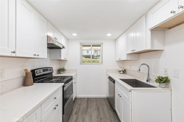 kitchen with white cabinetry, light stone counters, stainless steel appliances, light hardwood / wood-style flooring, and sink