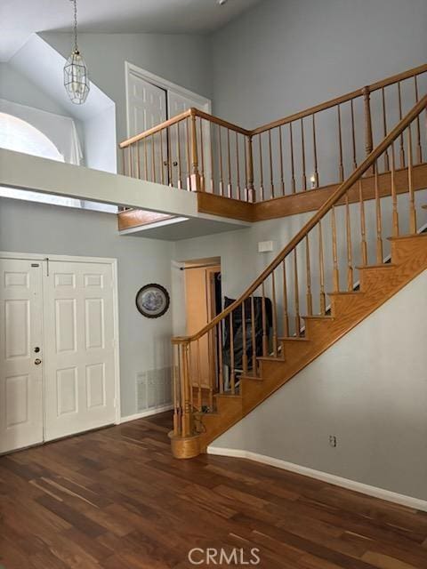 foyer with high vaulted ceiling, dark wood-type flooring, and a notable chandelier