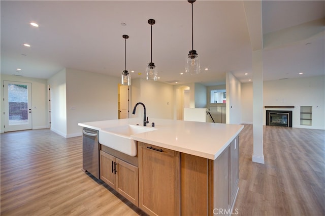 kitchen featuring an island with sink, light wood-type flooring, stainless steel dishwasher, and sink