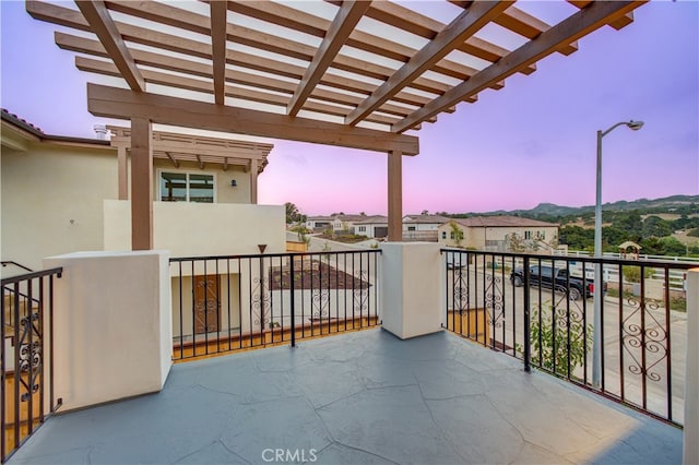 balcony at dusk featuring a pergola