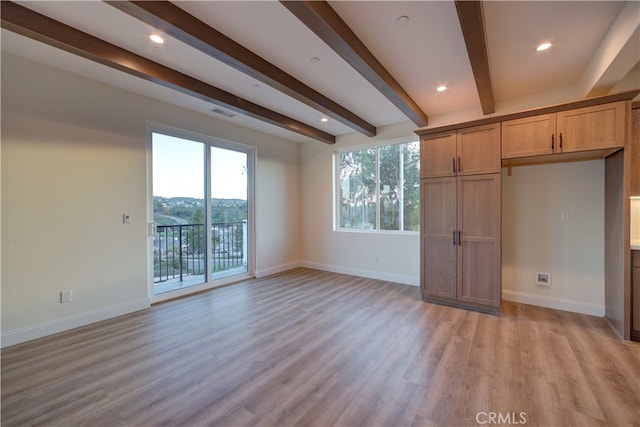 unfurnished living room featuring a wealth of natural light, light hardwood / wood-style floors, and beamed ceiling