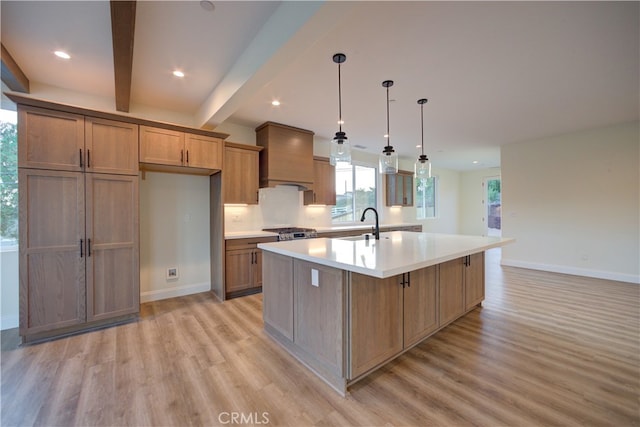 kitchen featuring pendant lighting, light wood-type flooring, beam ceiling, premium range hood, and a large island