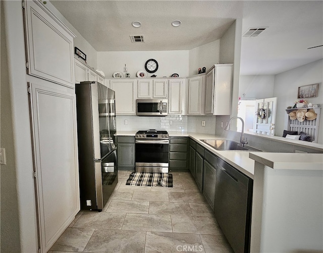 kitchen featuring gray cabinets, tasteful backsplash, sink, kitchen peninsula, and stainless steel appliances