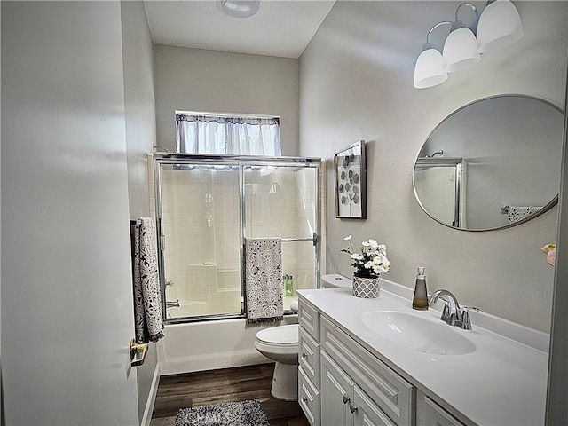 full bathroom featuring hardwood / wood-style floors, shower / bath combination with glass door, vanity, and toilet