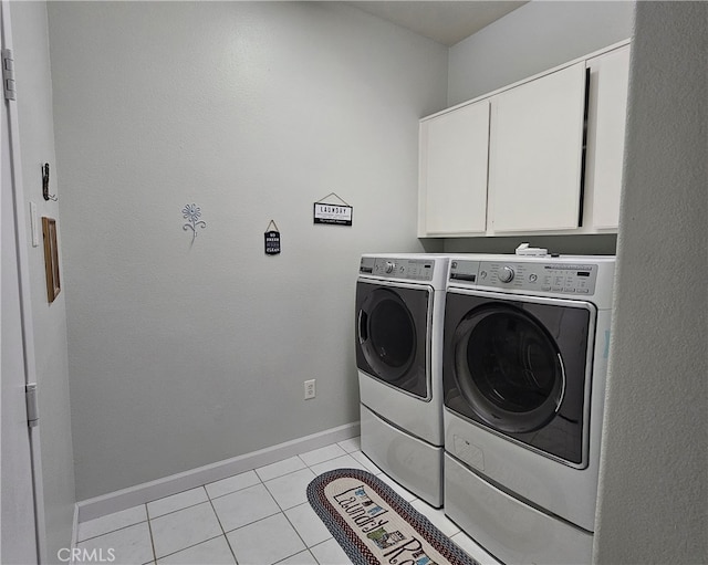 washroom featuring cabinets, light tile patterned flooring, and washer and clothes dryer