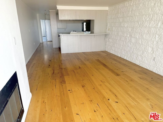 kitchen featuring hardwood / wood-style flooring, a breakfast bar, kitchen peninsula, and a fireplace