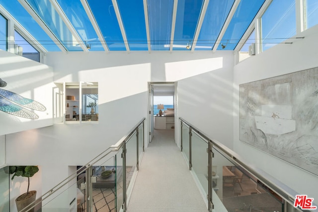 hallway featuring a high ceiling and light carpet