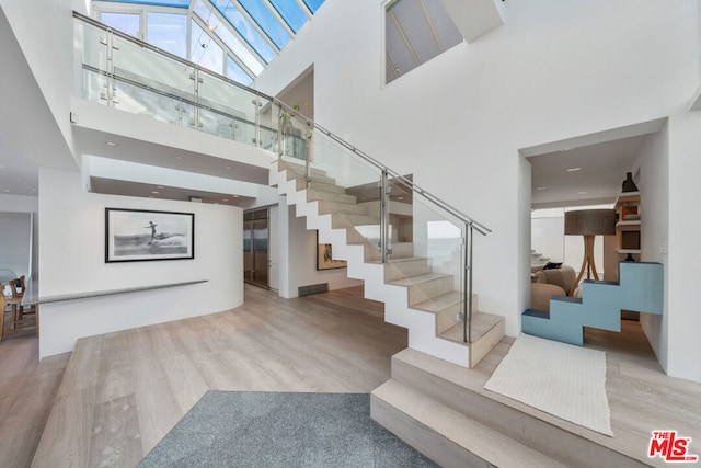 stairway featuring high vaulted ceiling and hardwood / wood-style floors