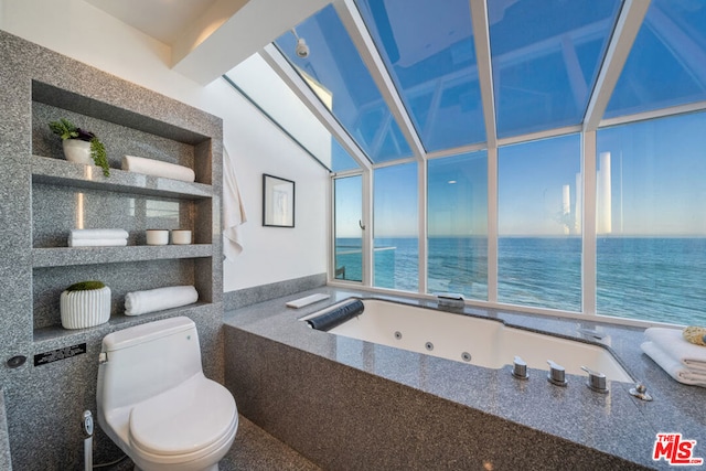 bathroom with a healthy amount of sunlight, tiled bath, a water view, and toilet