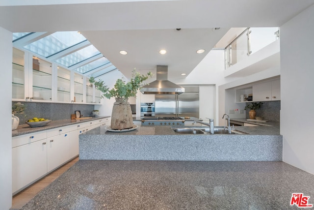 kitchen featuring extractor fan, white cabinets, tasteful backsplash, and sink