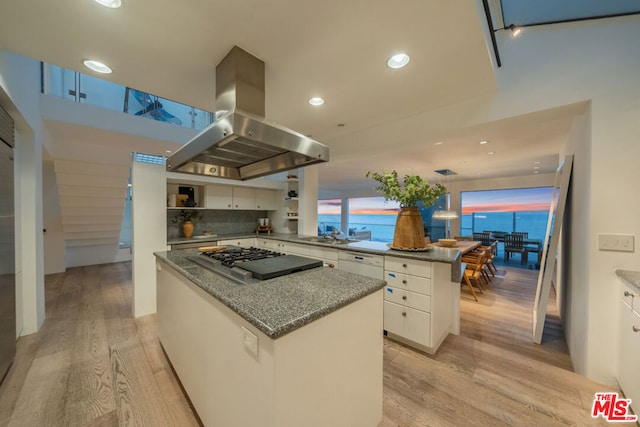 kitchen featuring island range hood, a kitchen island, light hardwood / wood-style flooring, backsplash, and white cabinets