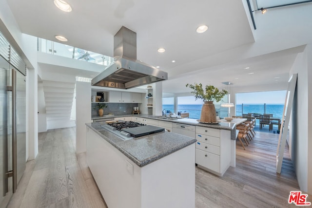 kitchen featuring white cabinets, island range hood, a water view, and light wood-type flooring