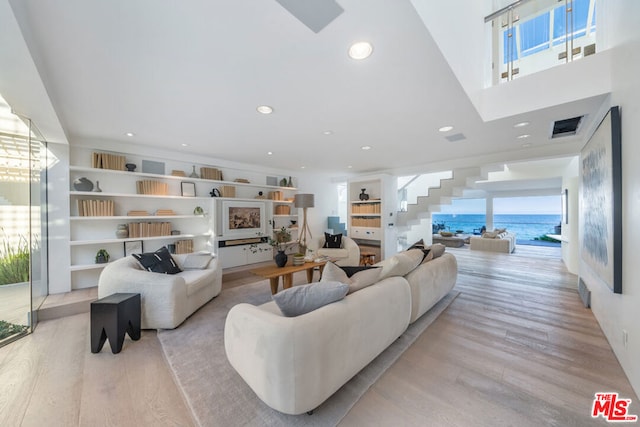 living room with light wood-type flooring, a water view, and a wealth of natural light