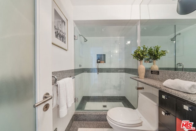 bathroom featuring a shower with door, vanity, and toilet