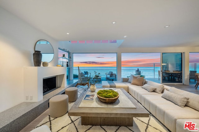 living room with light wood-type flooring, a water view, and a healthy amount of sunlight