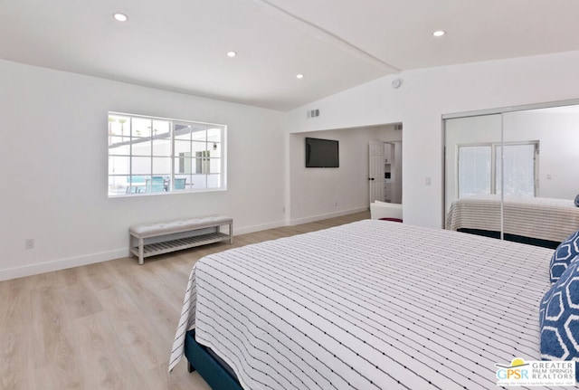 bedroom featuring light hardwood / wood-style floors, vaulted ceiling, and a closet