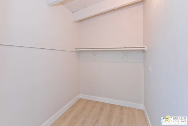 spacious closet with beamed ceiling and light hardwood / wood-style floors