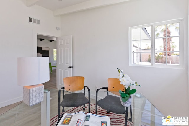 sitting room with beamed ceiling and wood-type flooring