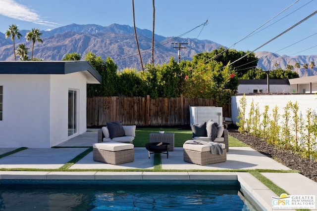 view of swimming pool featuring outdoor lounge area, a mountain view, a patio area, and an outbuilding