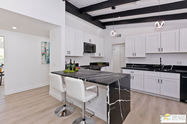 kitchen with white cabinets, a kitchen bar, decorative light fixtures, and black appliances